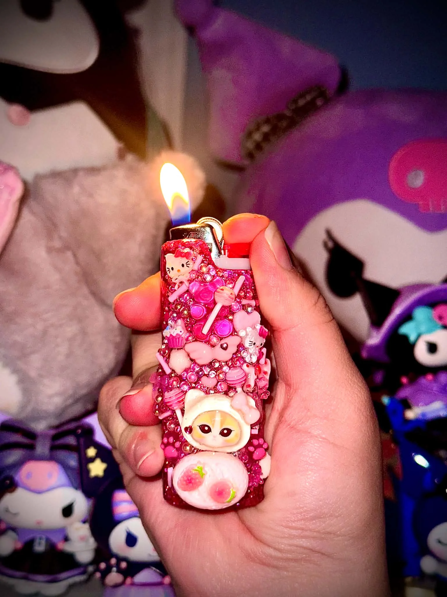 Pink charm-covered lighter cover held in a hand