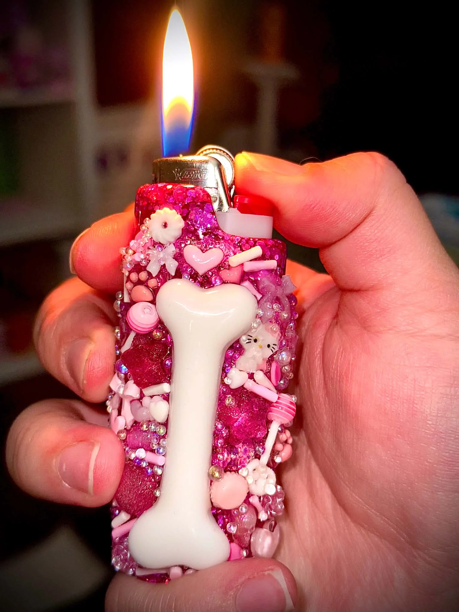 Bright pink charm-covered lighter held in a hand